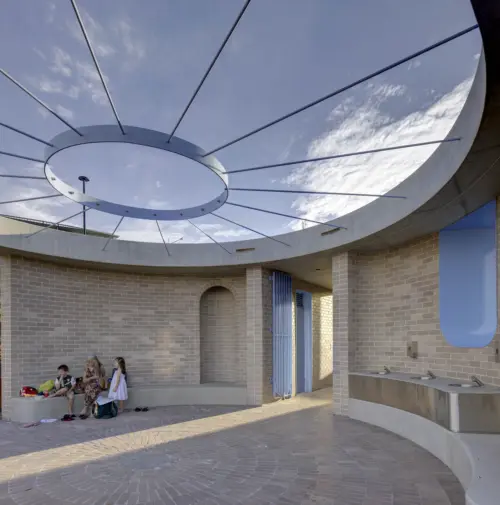 Public architecture amenities with people seated under a concrete shaded canopy