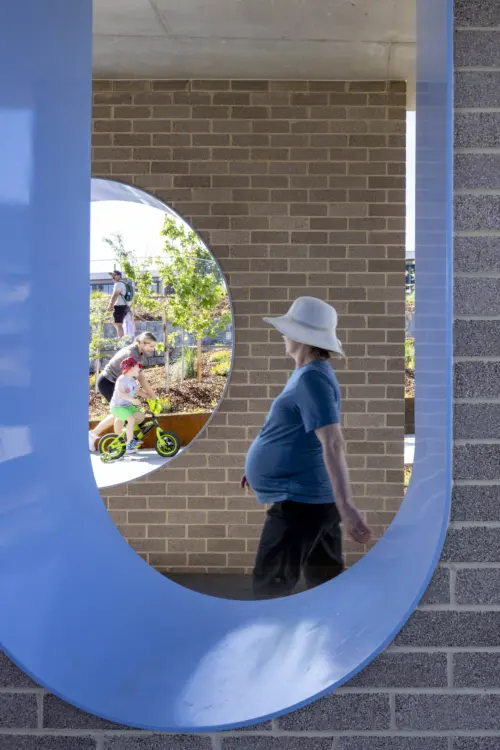 Woman walking through brick window cut-out public architecture amenities